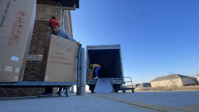 JB's Precision Moving crew carrying a box handled with care in Northwest Arkansas
